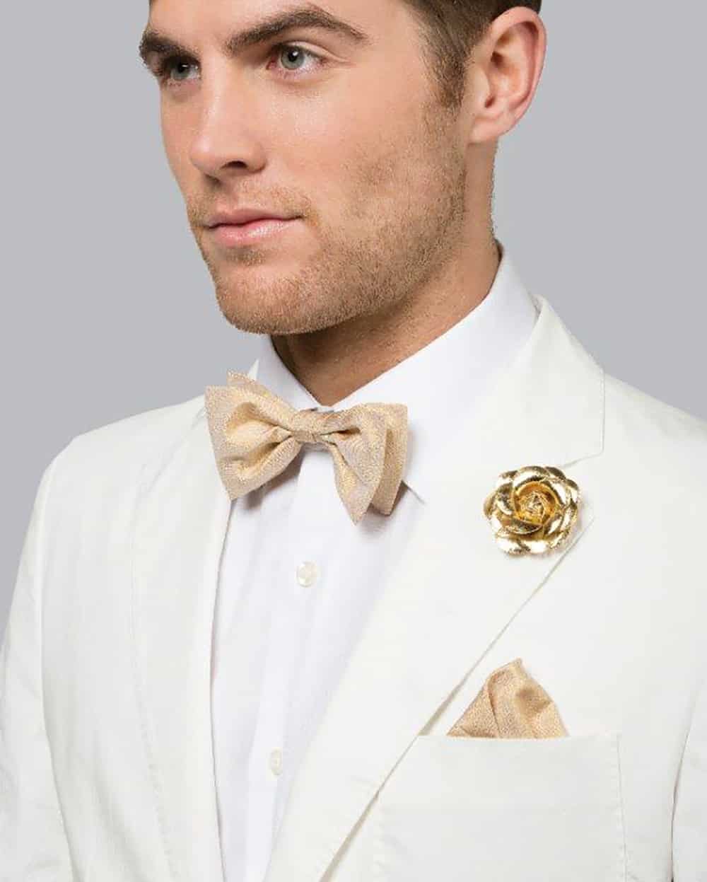 Groom wearing metallic bow-tie and lapel flower pin from Tony Barlow.