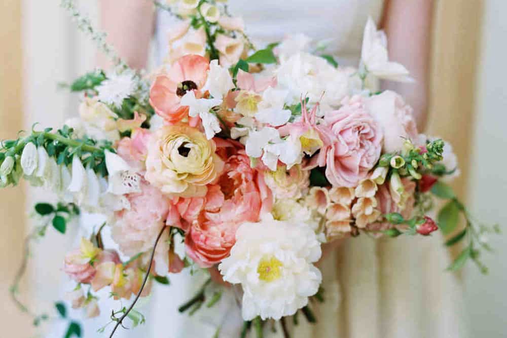 Cascading floral bouquet with peach, coral, green and white florals.