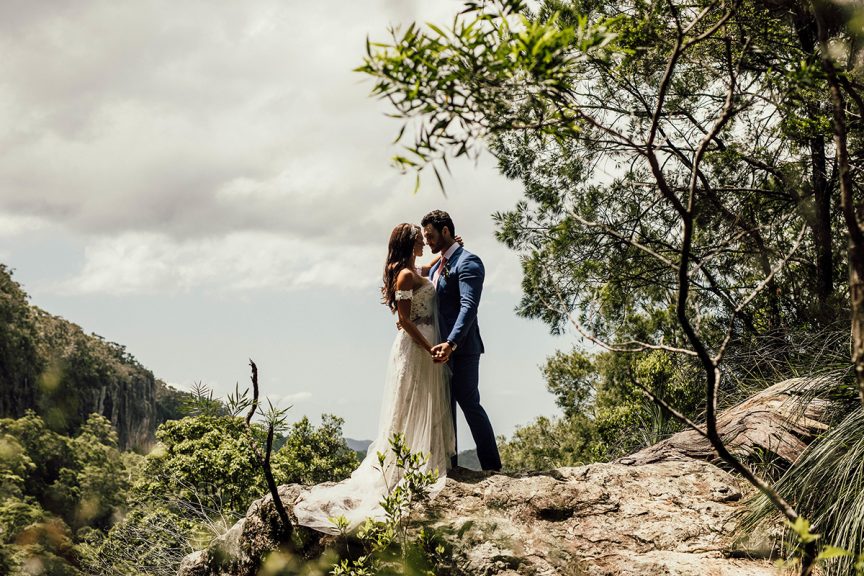 Couple embracing on rock outlook in rainforest