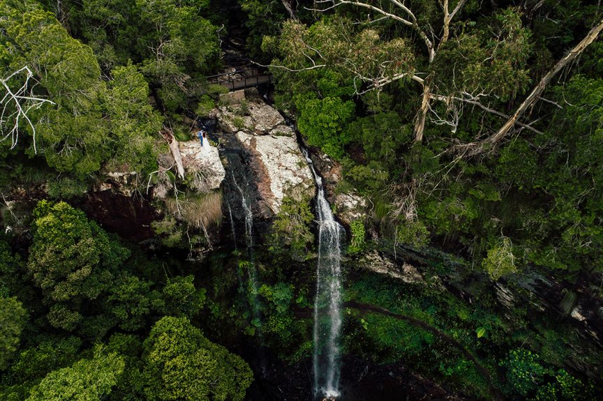 Couple standing near waterfall in rainforest