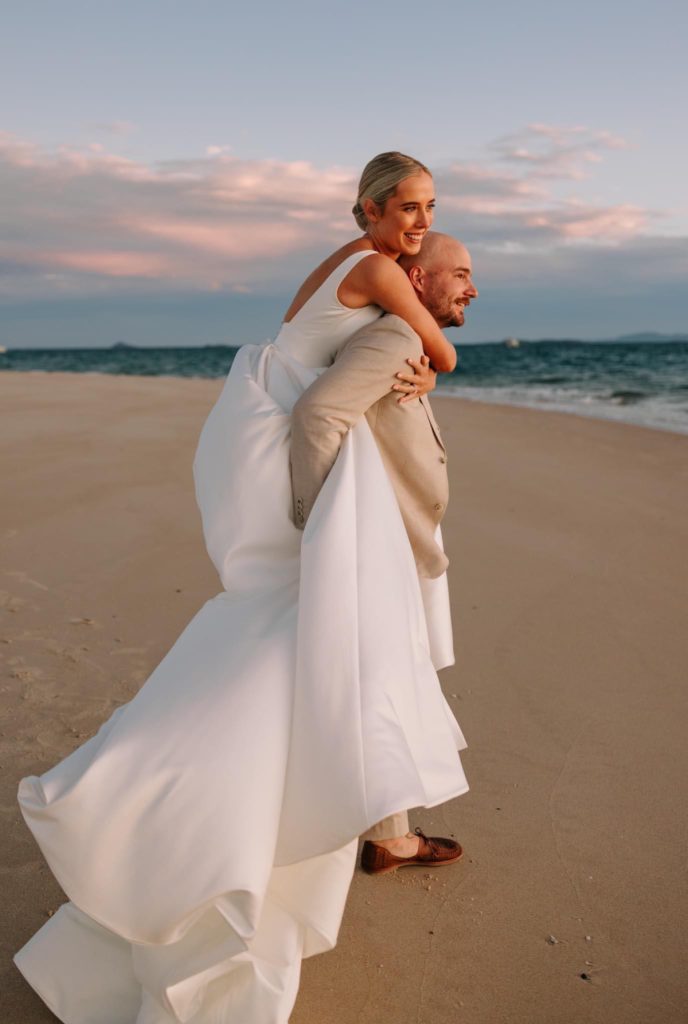 Real-wedding-Brooke-and-Ben-by-Sarah-Lette-Photography-newlyweds-on-the-beach-groom-carrying-the-bride